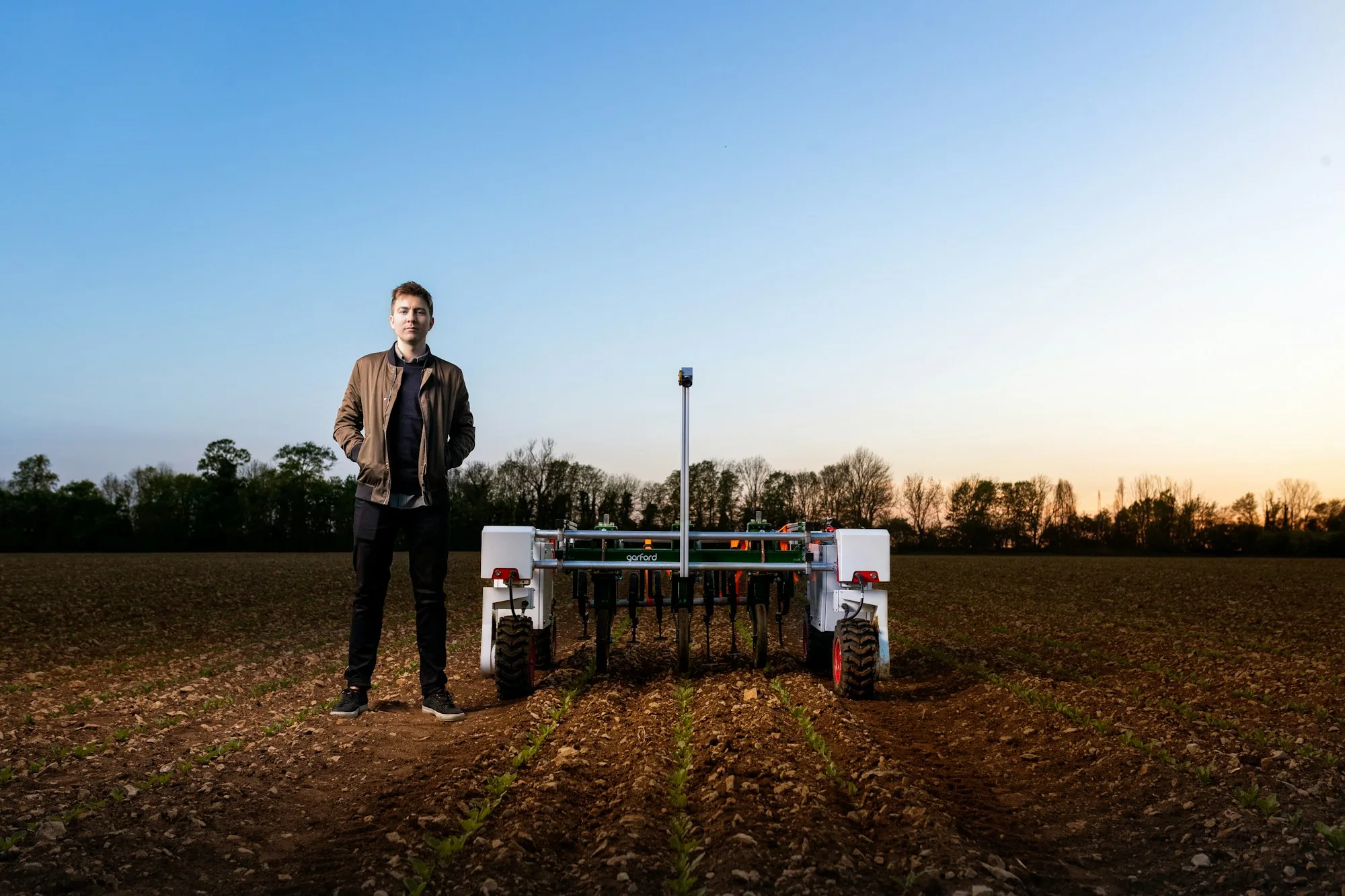 An engineer standing with an agricultural robot in a field