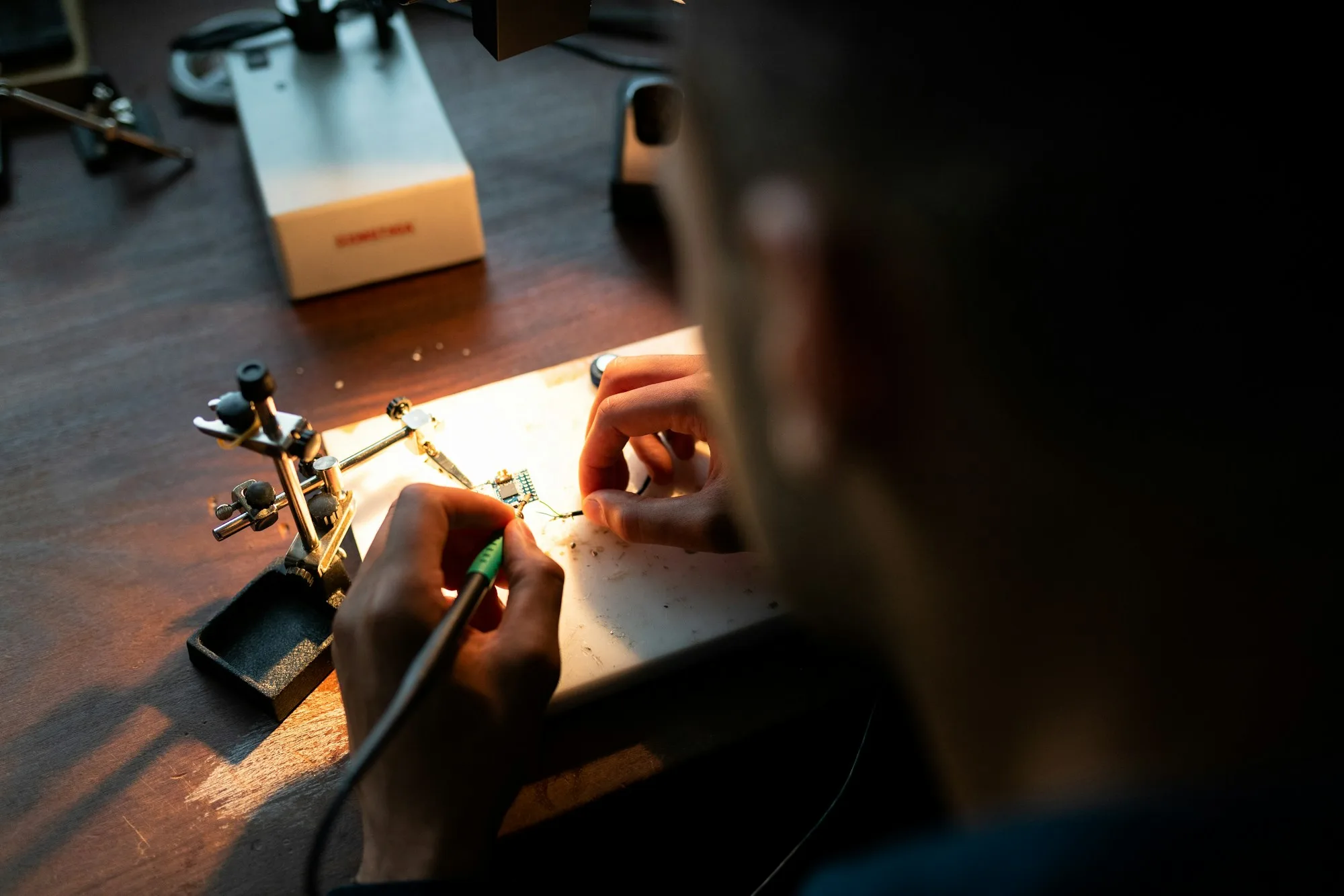 An engineer soldering electronic circuitry at a bench
