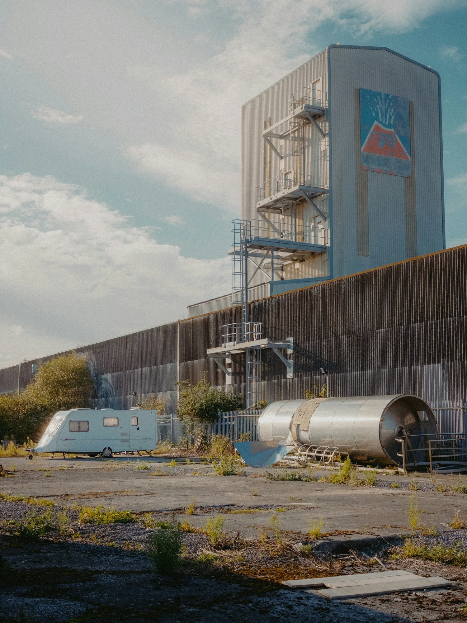 A train passing a large industrial building on the Wirral
