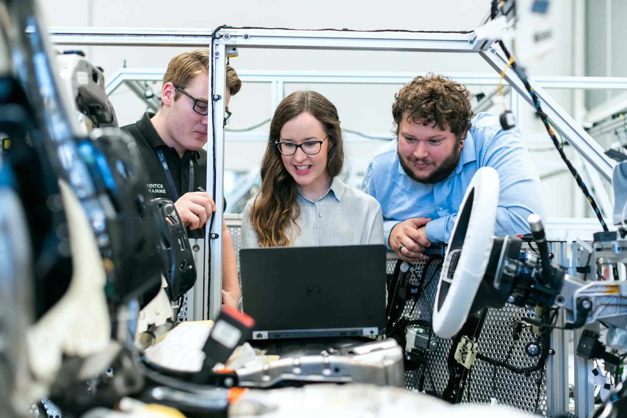 An engineering team reviewing vehicle software beside production equipment