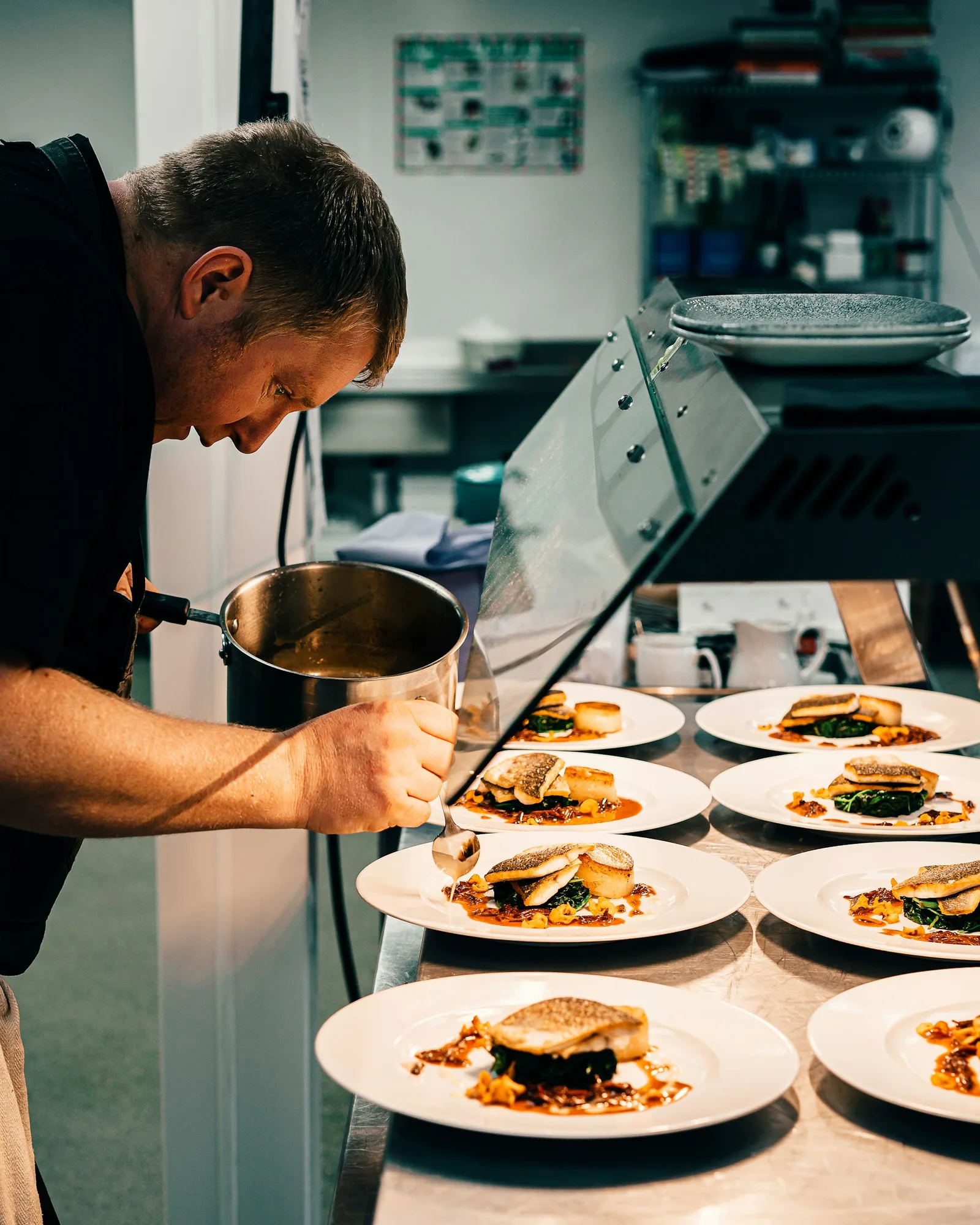 A chef finishing several plates in a commercial kitchen